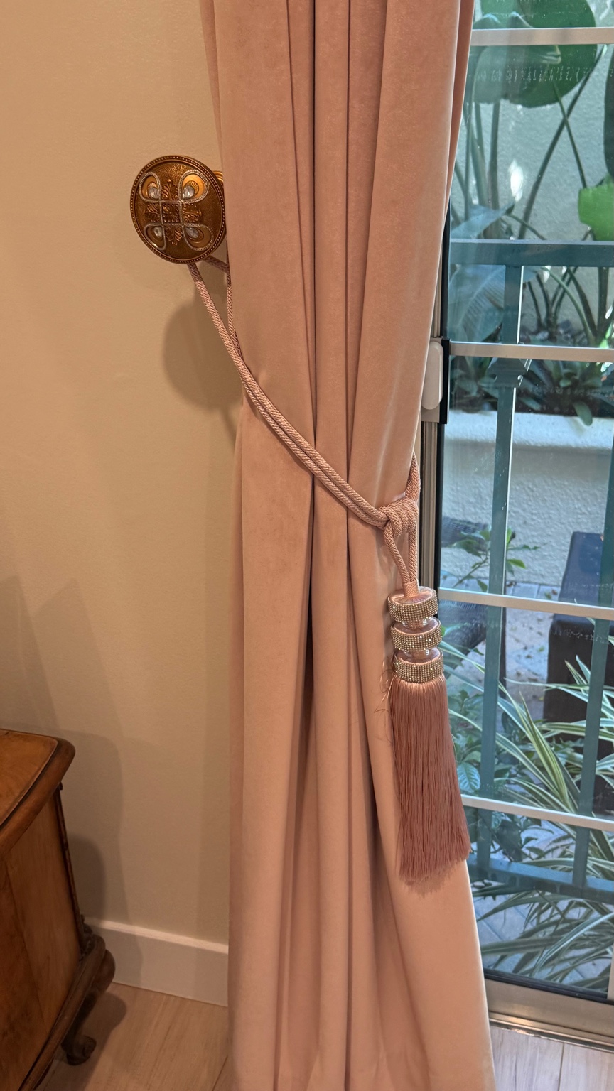 Blush drapery with decorative tassel and ornamental holdback
