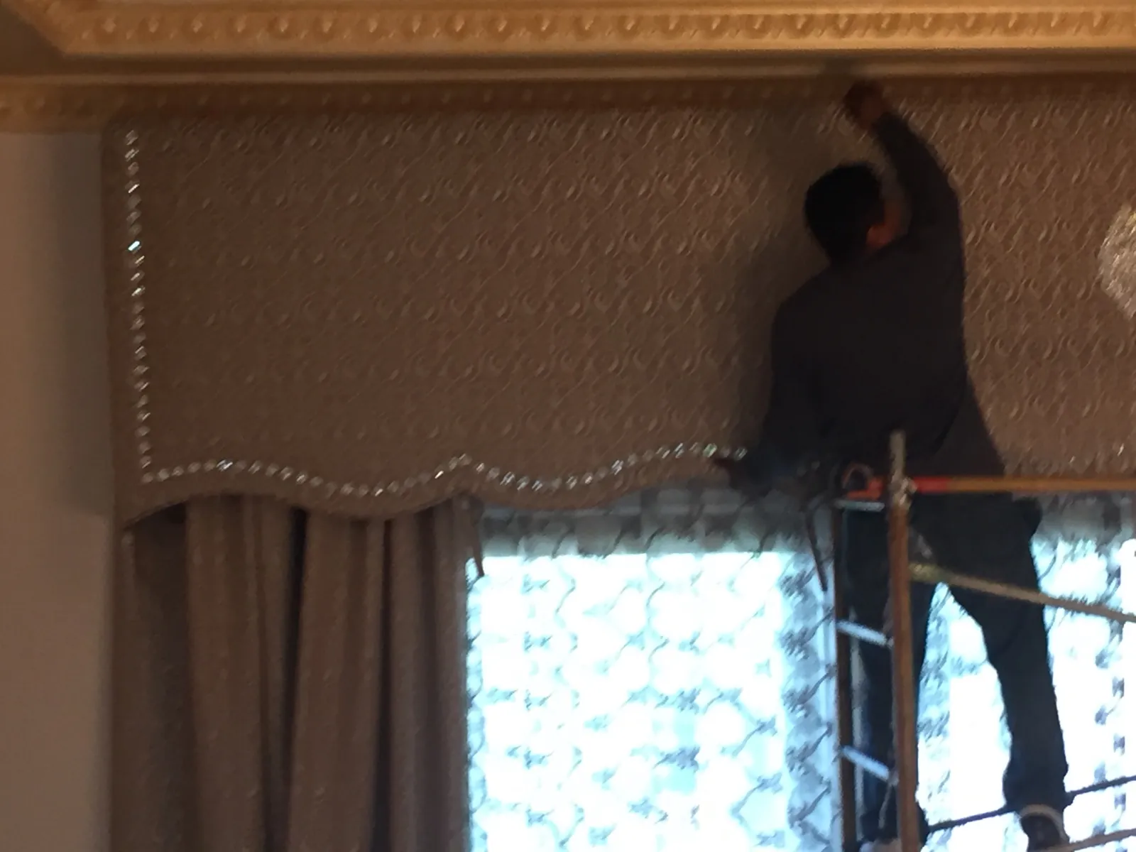 Close detail of the finished Porterville cornice box — scalloped lower edge, continuous crystal bead trim, tone-on-tone damask face — set above lined taupe drapery and patterned sheers